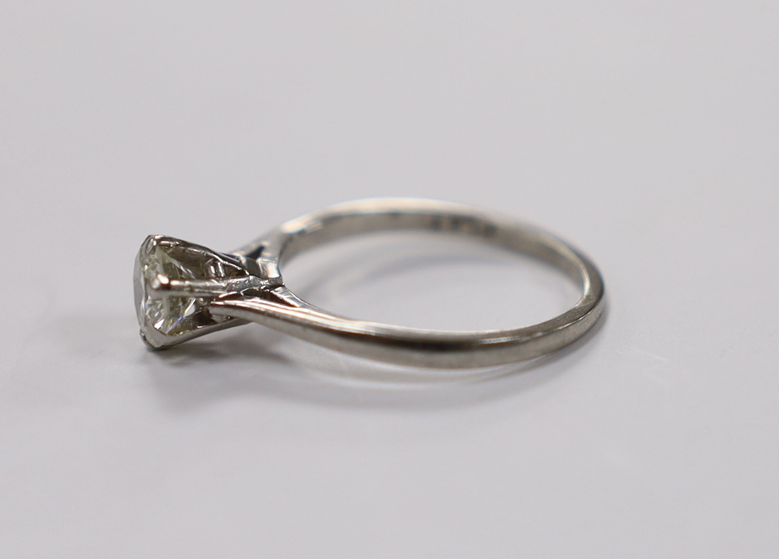 A white metal (stamped plat) and solitaire diamond set ring, size L/M, gross weight 3.5 grams, the stone with a diameter of 6mm.